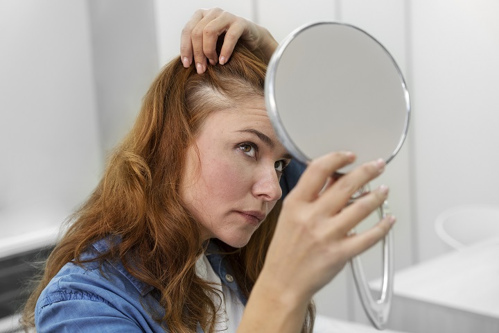Женщина проверяет густоту волос перед зеркалом 