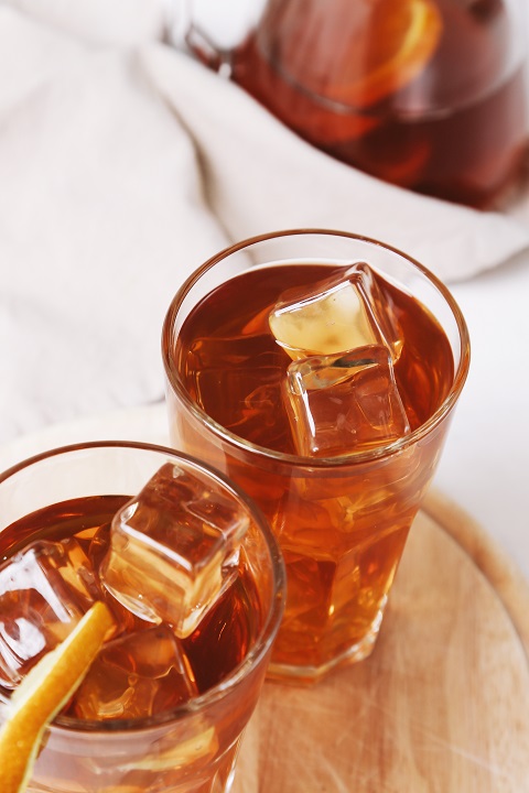 Чай с лимоном и кусочками льда налит в стакан