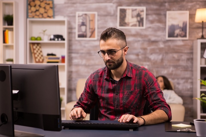 Молодой мужчина сидит перед экраном компьютера 