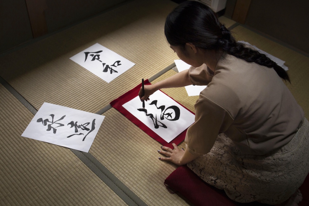 девушка рисует японские иероглифы