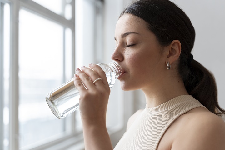 Молодая женщина пьет воду после тренировки