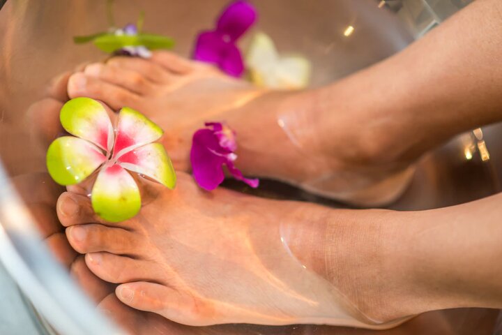 Женские ноги в ванночке с бутонами цветов 
