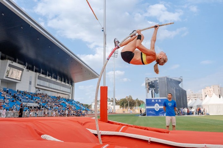 Спортсменка прыгает с шестом на стадионе Динамо 