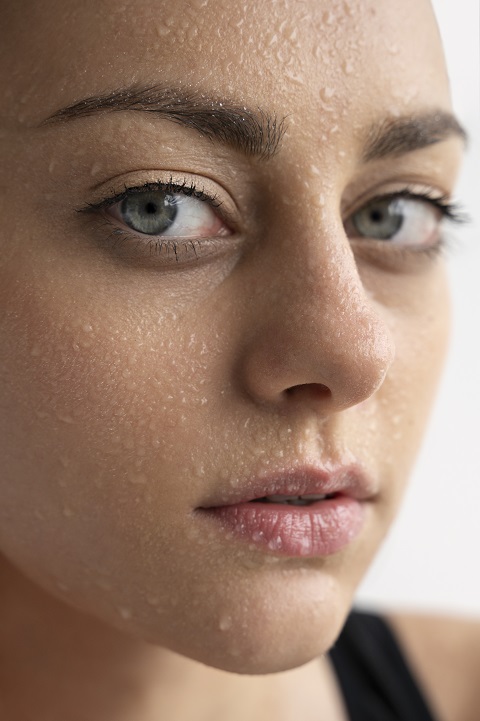 Портрет молодой девушки с каплями воды на лице 