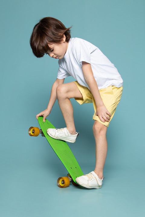 Мальчик стоит на скейтборде, обутый в кроссовки 