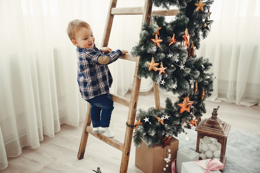 Маленький мальчик помогает наряжать елку