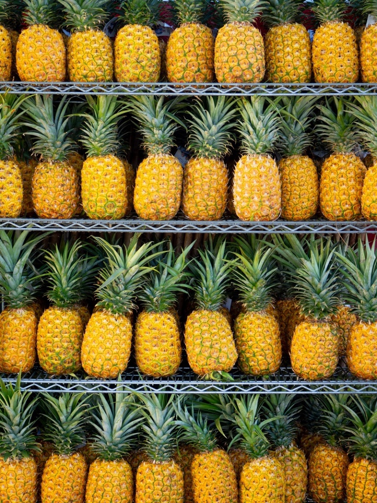 Свежие ананасы лежат на полках, выставленные на продажу