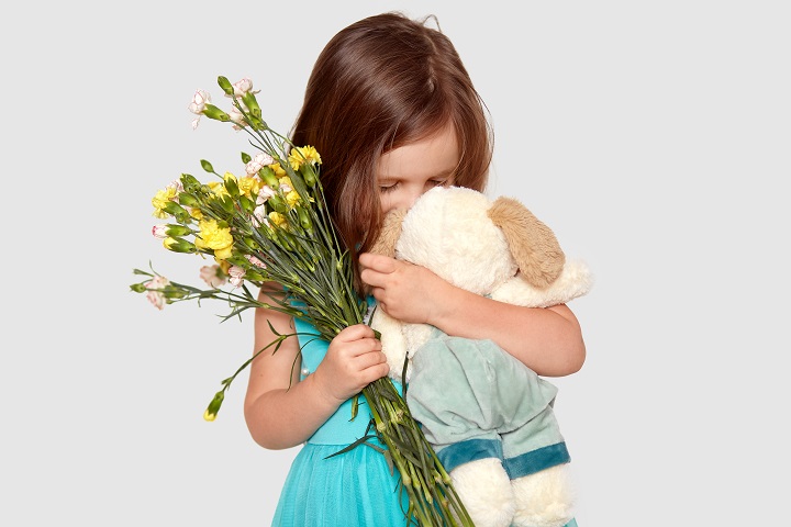 Маленькая девочка держит в руках букет и мягкую игрушку