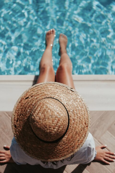 девушка в шляпе сидит перед бассейном