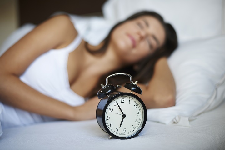 Молодая женщина спит за пять минут до звонка будильника 