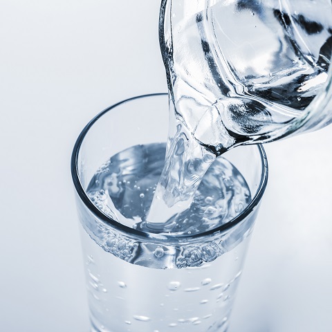 Природная питьевая вода наливается в стакан из графина 