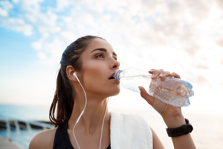 Молодая девушка пьет воду после тренировки 