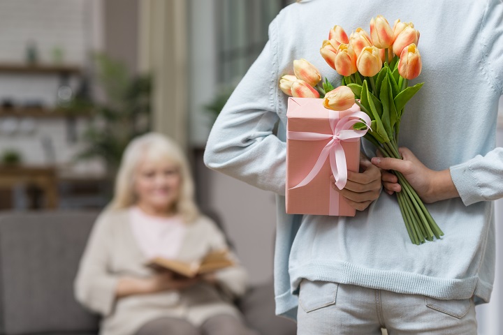 Внучка дарит бабушке букет тюльпанов и подарок