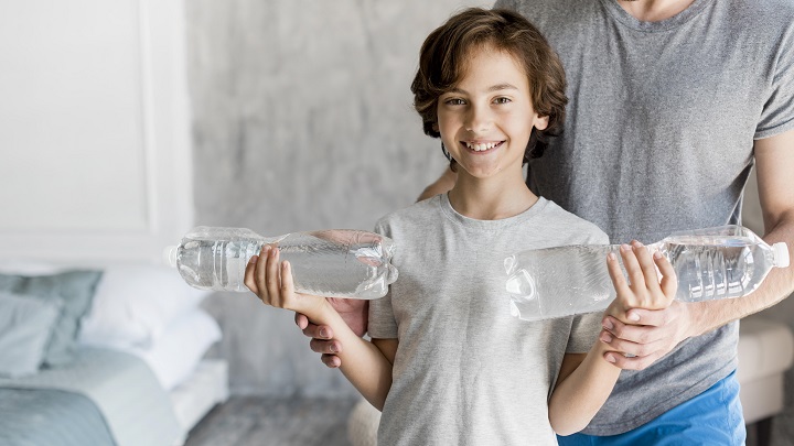 Мальчик подросток держит в руках две бутылки с минеральной водой