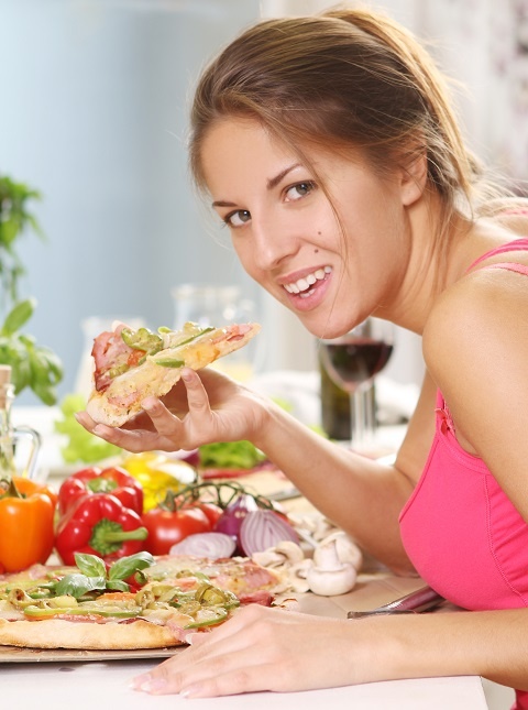 Молодая женщина с аппетитом ест пиццу