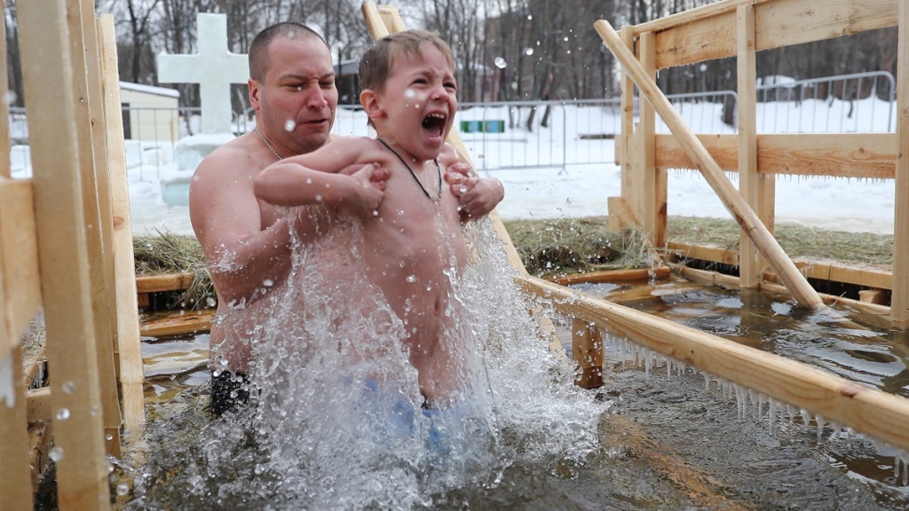 Отец купает сына в проруби на Крещение