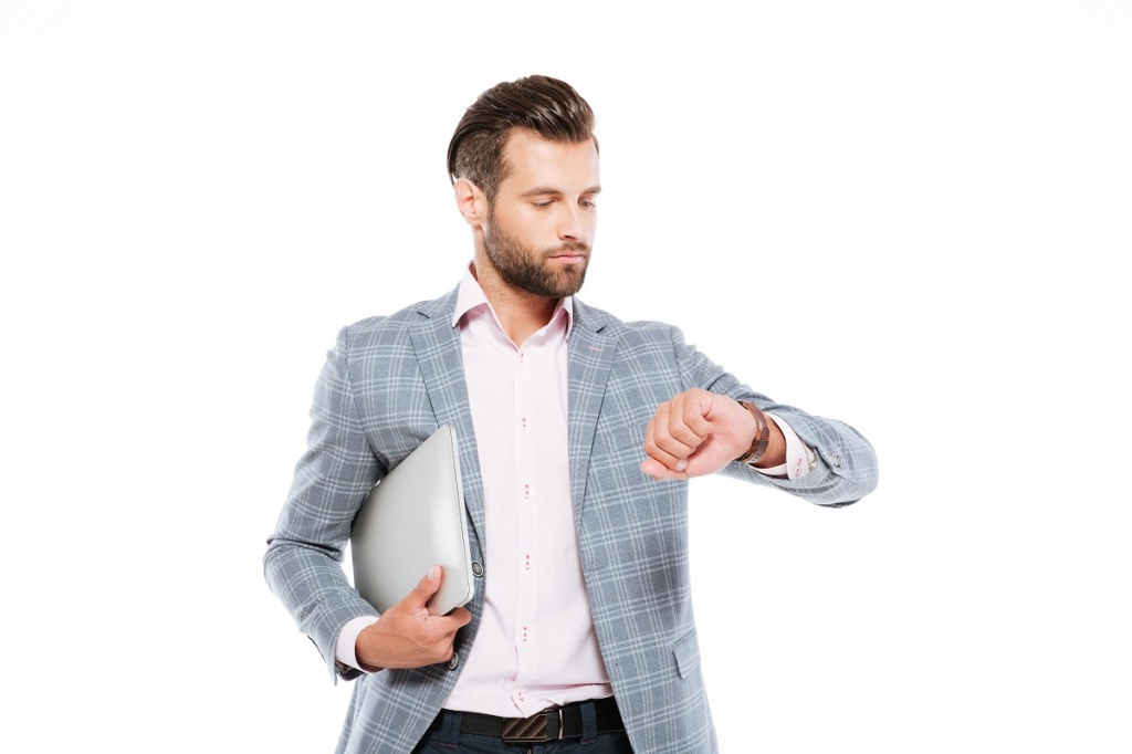 serious-young-man-holding-laptop-computer-looking-watch.jpg