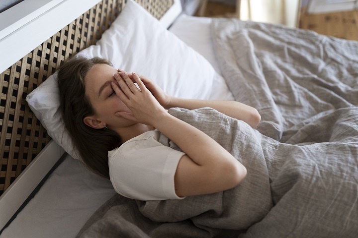 high-angle-anxious-woman-laying-bed.jpg Молодая женщина лежит в постели и плохо себя чувствует