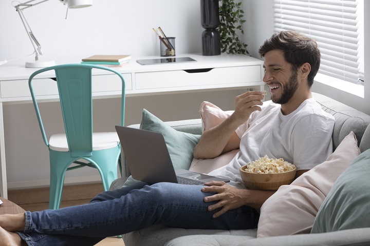 man-watching-his-favorite-movie-laptop.jpg Мужчина смотрит комедийный фильм и ест попкорн