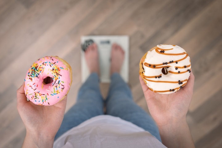 woman-stands-scales-holds-donuts-her-hands-top-view-copy-space.jpg Молодая женщина стоит на весах, держа пончики в руках
