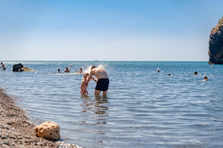Папа умывает дочку в море 