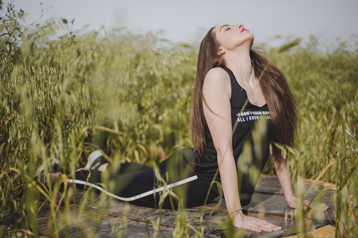 woman-lying-stretching-field.jpg Молодая женщина делает разминку в поле