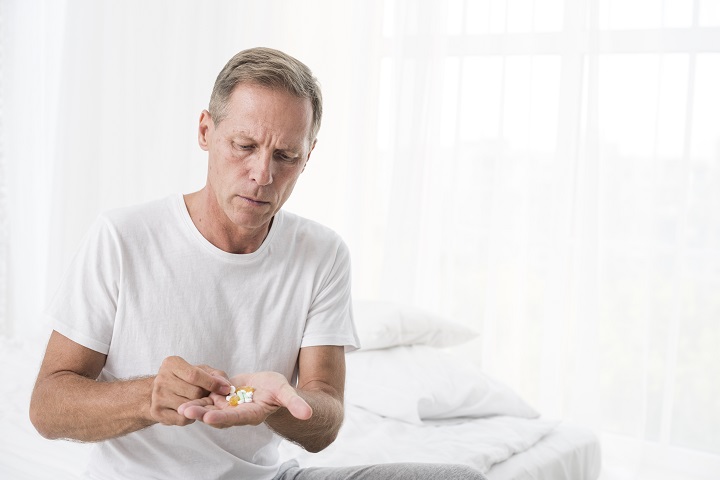 medium-shot-man-with-pills-bedroom.jpg Мужчина средних лет пьет лекарства