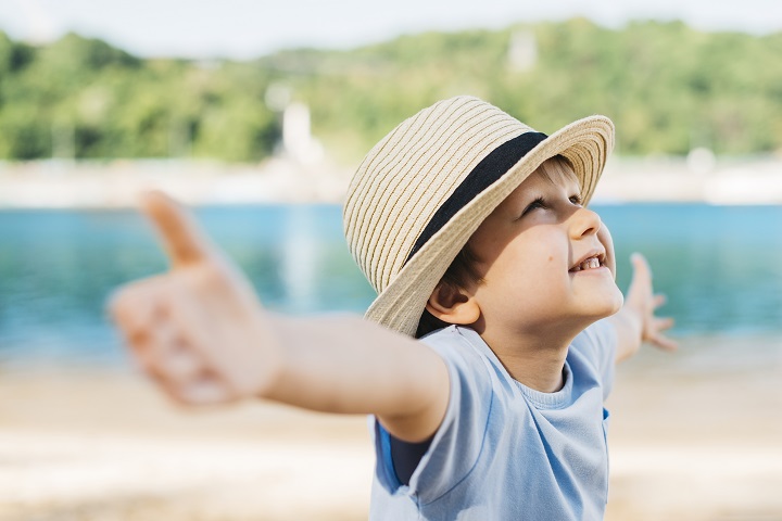 delighted-boy-spreading-hands-looking-up-daylight.jpg Маленький мальчик в шляпе раскинул руки и смотрит на небо