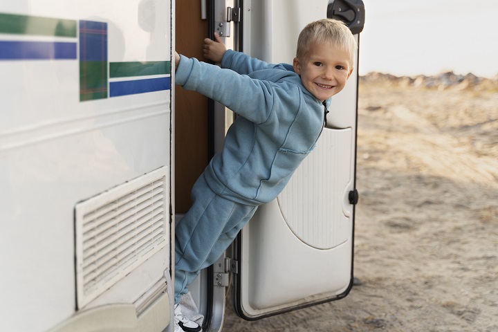 full-shot-boy-campervan.jpg Cчастливый мальчик выглядывает из двери автодома
