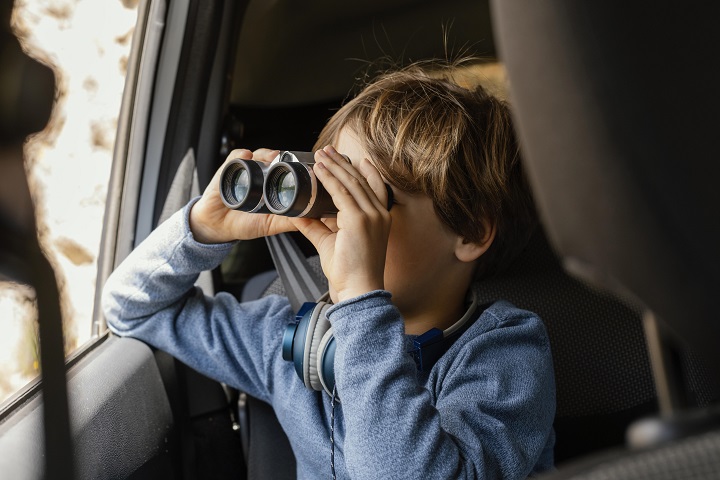 portrait-young-boy-car-with-binoculars.jpg Маленький мальчик смотрит в бинокль в окно автомобиля