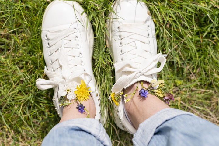 top-view-woman-feet-with-flowers.jpg Девушка в белых кедах стоит на зеленой траве