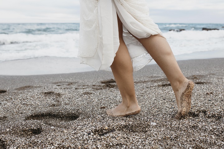 woman-wedding-dress-beach.jpg Девушка в белом платье идет босиком по берегу моря