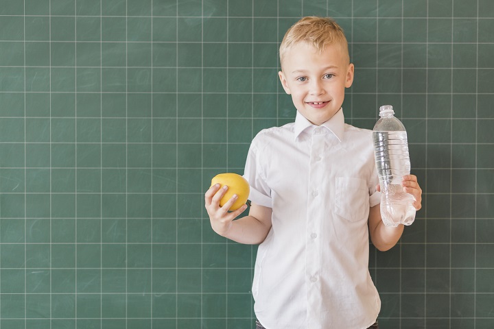 junior-with-water-apple-near-chalkboard.jpg Школьник стоит у доски с яблоком и бутылкой воды