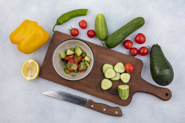 top-view-fresh-vegetable-like-chopped-cucumber-cherry-tomatoes-yellow-bell-pepper-lemon-kitchen-board-with-knife-white.jpg
