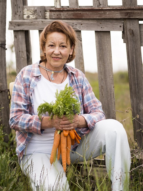 woman-holding-some-carrots-her-hand.jpg Женщина средних лет держит в руках пучок моркови