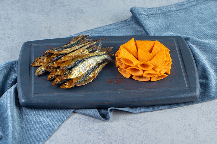 cone-chips-dried-small-salted-sprat-tray-pieces-fabric-marble-surface.jpg Копченая мелкая рыба с чипсами на деревянной доске
