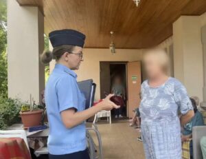 пристав стоит с женщиной во дворе дома